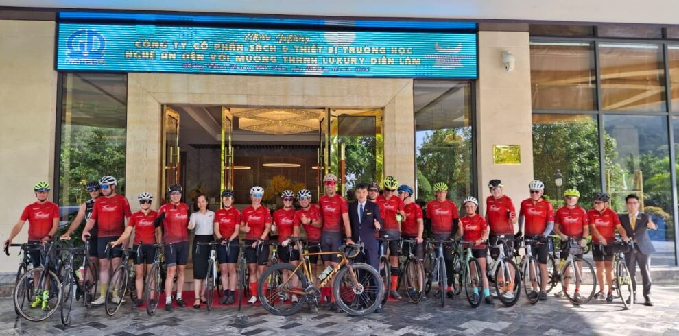Road cycling group posing in front of their tour hotel with guides and support staff during the Bangkok to Hanoi expedition.