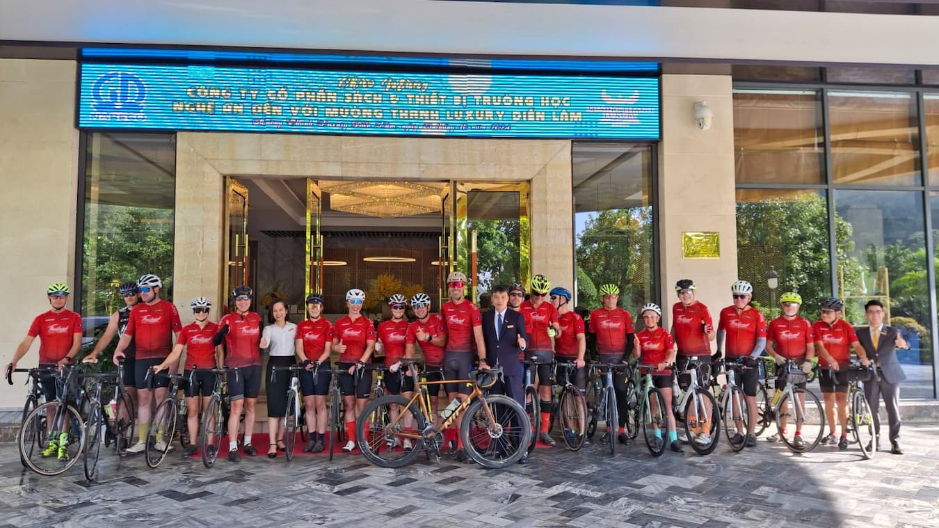 Road cycling group posing in front of their tour hotel with guides and support staff during the Bangkok to Hanoi expedition.