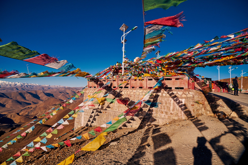 Traditional colorful Tibetan prayer flags fluttering in the wind on a high-altitude pass during the Epic Tibet cycling tour.