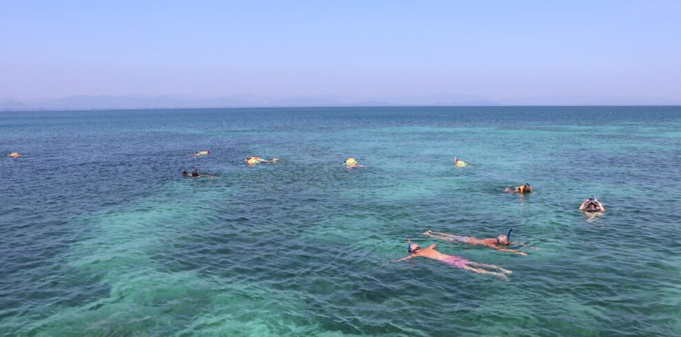 Cyclists enjoying a refreshing snorkeling session in the clear blue waters of Koh Talu Island on a fully supported tour.
