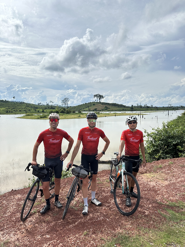 Three cyclists posing with their road bikes next to the Nam Ngum reservoir during our Bangkok to Luang Prabang cross-border cycling tour.