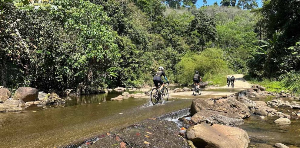 Road cyclists carefully riding across a shallow concrete river crossing during the Explore South Thailand Road Bike Tour.