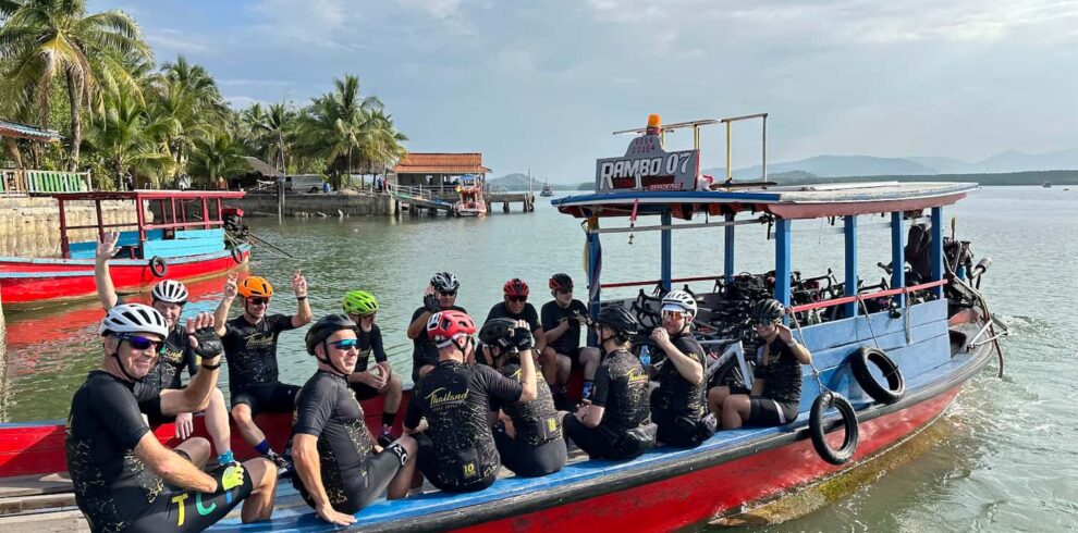 A group of cyclists with their bikes relaxing on a local wooden boat transfer named Rambo 07 during an Explore South Thailand by road bike tour.