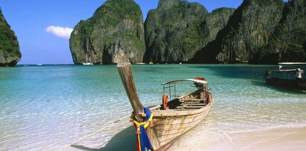 A traditional longtail boat on the white sands of Ao Nang Beach in Krabi, a key tropical highlight on our cycling tours in Thailand.