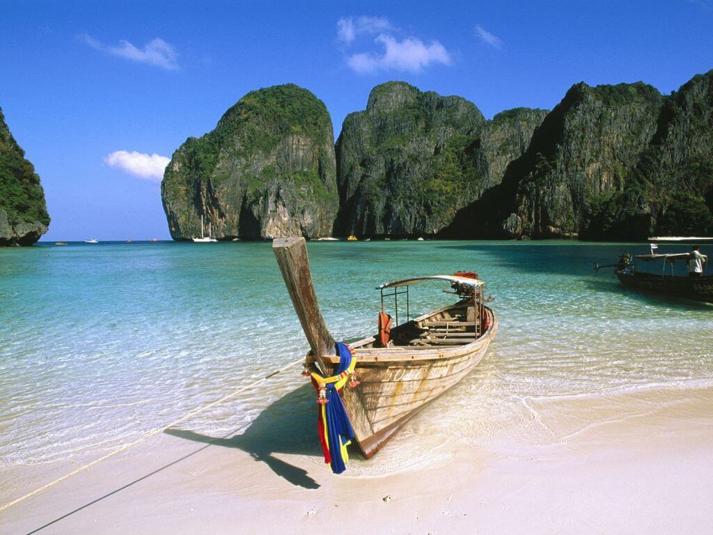 A traditional longtail boat on the white sands of Ao Nang Beach in Krabi, a key tropical highlight on our cycling tours in Thailand.