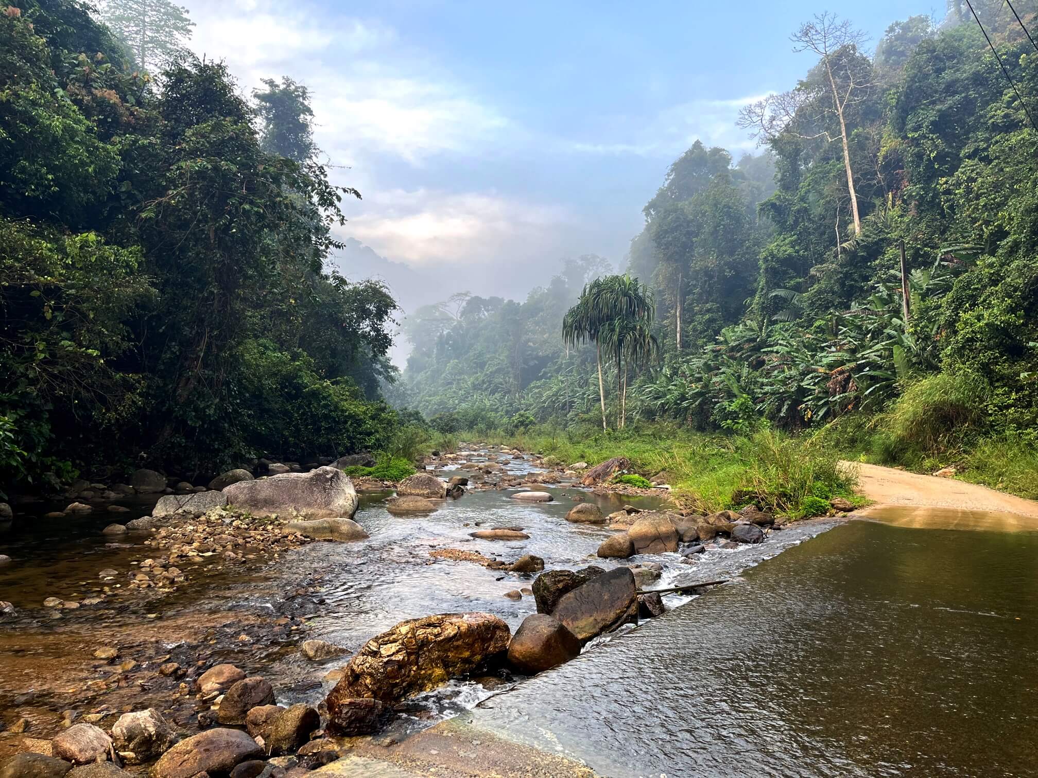 View of a cycling road just above a natural, shallow waterfall.