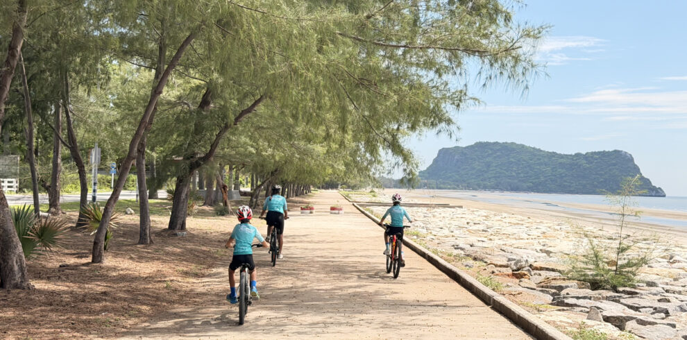 Kids cycling along a scenic beach road in Thailand with ocean views, palm trees, and a safe family-friendly cycling route during a Thailand Cycle Tours adventure.