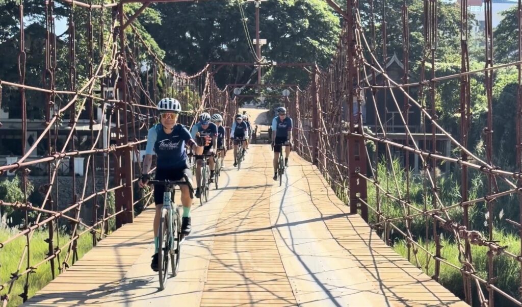 Radfahrer überqueren eine malerische Hängebrücke während einer Radtour in Thailand.